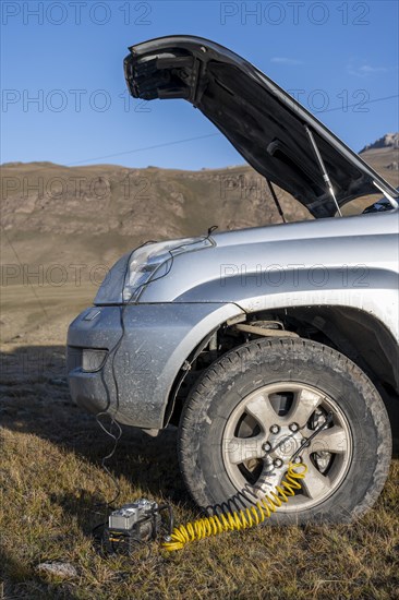 Compressor, inflating a car tyre, off-road vehicle, Kyrgyzstan, Asia