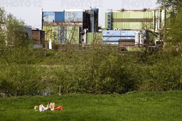 Couple lies on the Ruhrauen in front of the stainless steel plant in Witten, Ruhr area, North