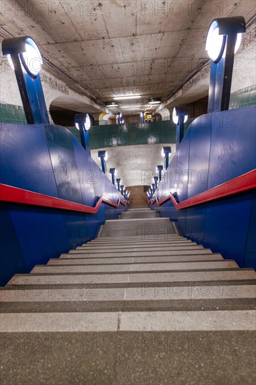 An empty staircase down to a Schloss Strasse underground station with characteristic blue colour