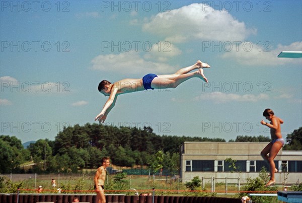 Boy jumping from three-metre board, outdoor swimming pool, Bamberg, Upper Franconia, Bavaria,