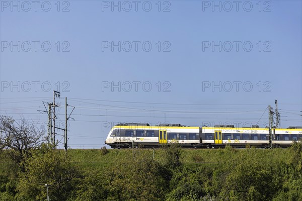 Regional train of the mobility brand bwegt unterwegs, railway embankment and overhead lines,