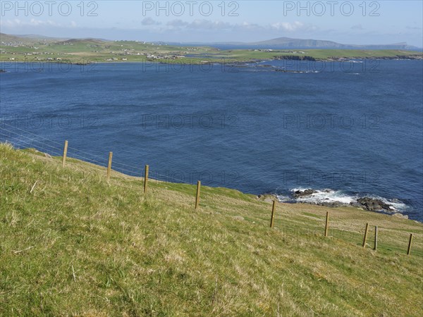 Green meadow leads to rocky coastline with sweeping views across deep blue sea, green meadows by a