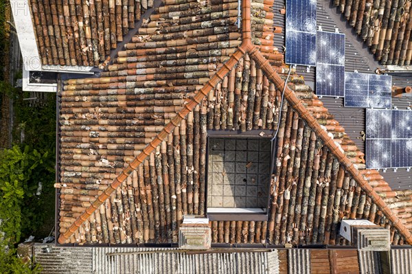 A mix of old tiled roofs and new solar panels damaged seen from an aerial viewpoint