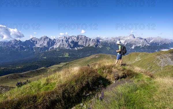 Mountaineers on a hiking trail between green mountain meadows, mountain panorama, view of rocky