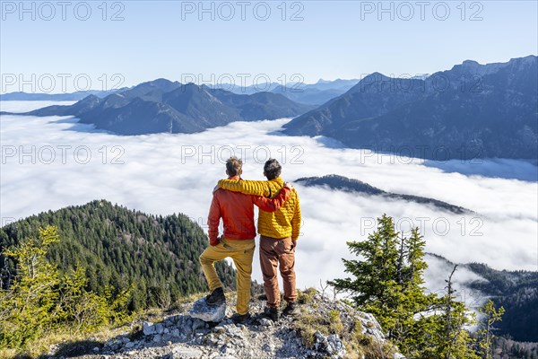 Two friends put their arms around each other's shoulders, mountaineers on the rocky summit of the