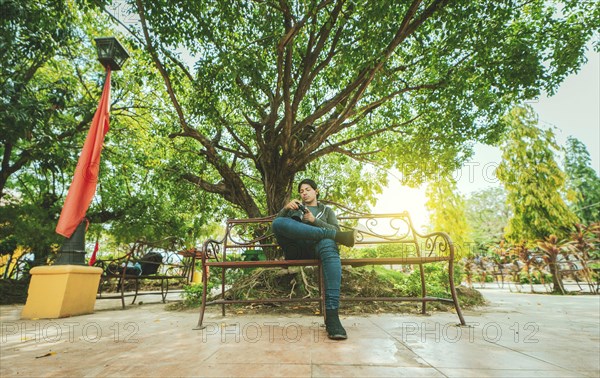 Photographer sitting on a bench checking his camera. Male photographer checking dslr camera sitting