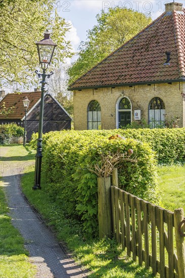 Traditional house in the village with surrounding meadow and hedges, illuminated by a lantern,