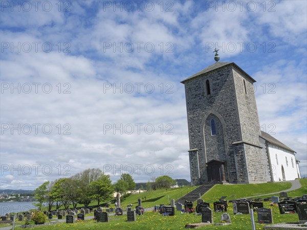 Church with cemetery under a cloudy sky on a green meadow, old stone church and many gravestones by