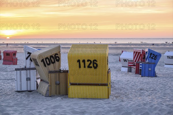 Beach chairs at sunset on the beach, focus on yellow basket, many colourful beach chairs on a warm