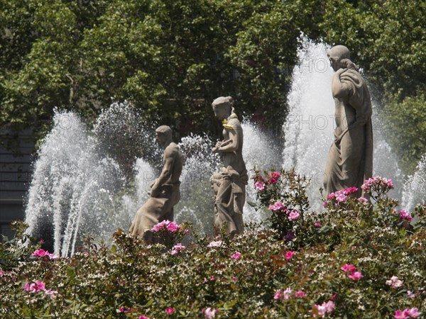 Three statues in a fountain surrounded by blooming flowers and bubbling water fountains, fountain