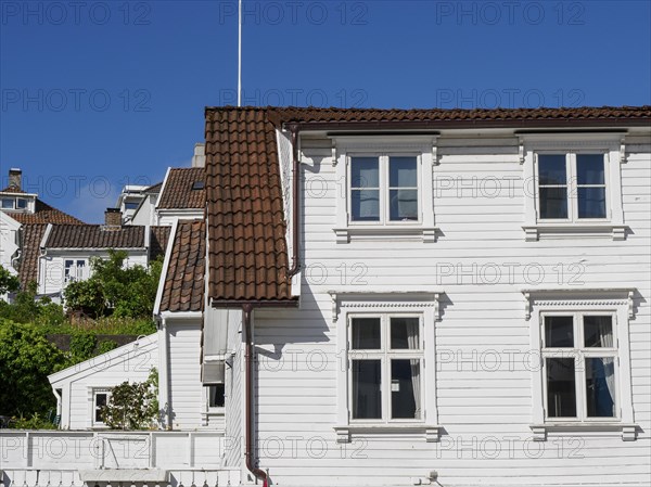 White wooden houses with red tiled roofs against a clear blue sky, white wooden houses with green