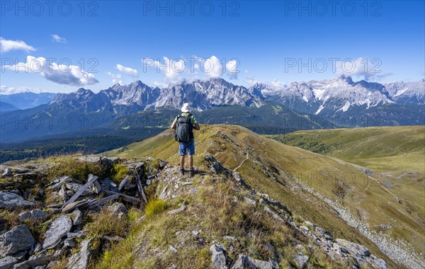 Mountaineers on a hiking trail between green mountain meadows on a mountain ridge, mountain
