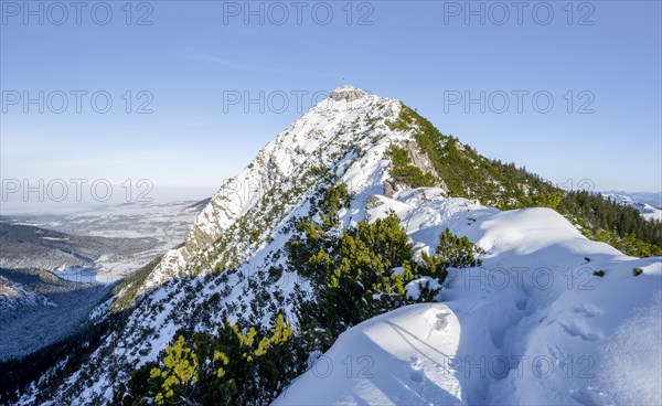Mountain ridge of the Aiplspitz with summit cross, snow-covered mountain landscape with mountain