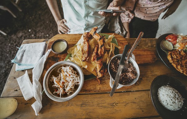 Person eating a traditional roast beef with slices of banana and gallopinto served on a wooden