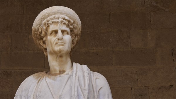 Antique marble statue with headdress and detailed curls, statue from the island of Kos, courtyard,