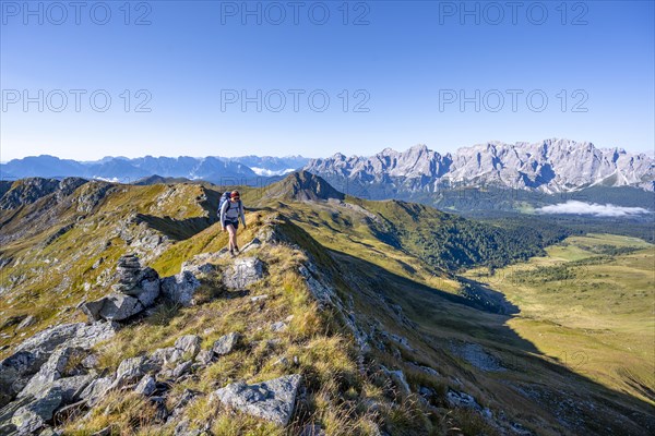 Mountaineer on a grassy ridge, mountain panorama, view of rocky mountain peaks of the Sesto