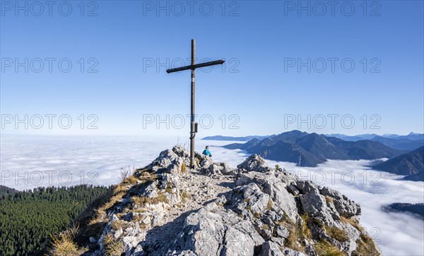 Summit cross at Ettaler Manndl, view over mountain landscape and sea of clouds, high fog in the