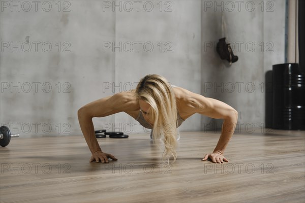 Low angle view of sporty woman doing push ups on the floor in gym