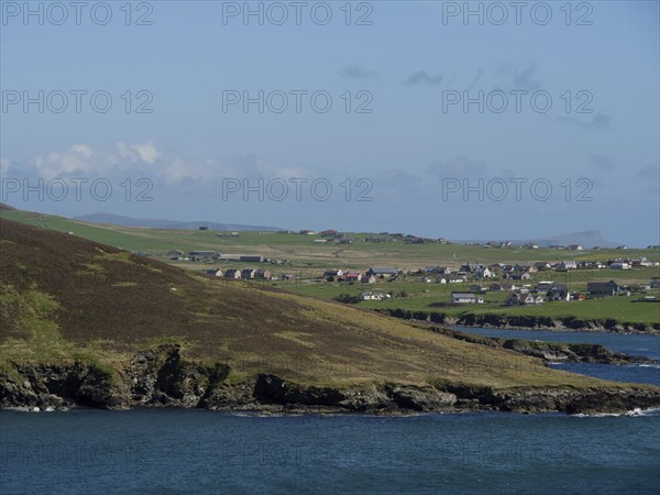 A small village on the coast with green fields and sea views, green meadows on a deep blue sea and