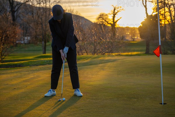 Female Golfer Concentration on the Putting Green on Golf Course in Sunset in Switzerland