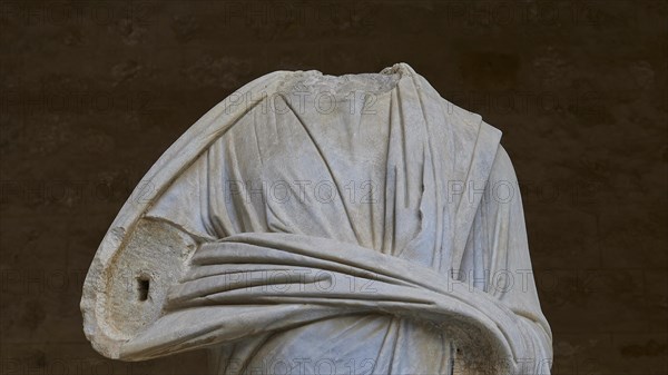 Marble sculpture focussing on the detailed folds of ancient clothing, torso of a Roman statue,