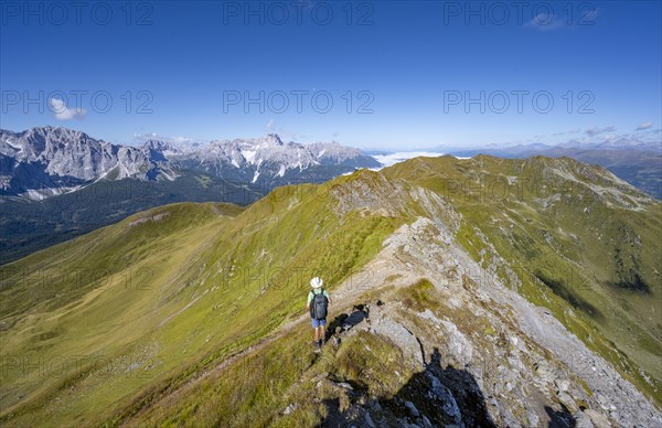 Mountaineers on a hiking trail between green mountain meadows on a mountain ridge, mountain