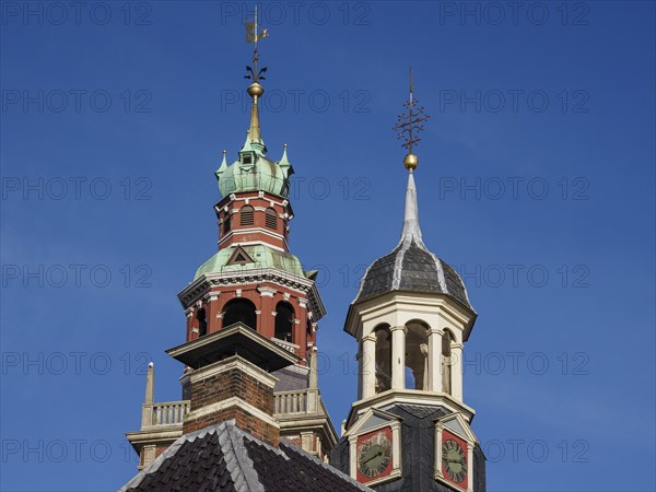 Two historic church towers with weather vane and clock under a blue sky, two towers of historic