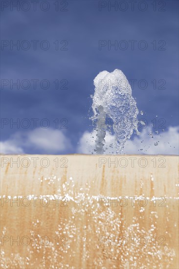 Stream of water coming out of a public fountain with a blue sky in the background