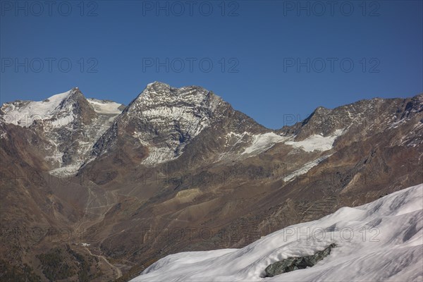 Snow covered mountains and rocky peaks under a clear blue sky, snow on high mountains in the alps,