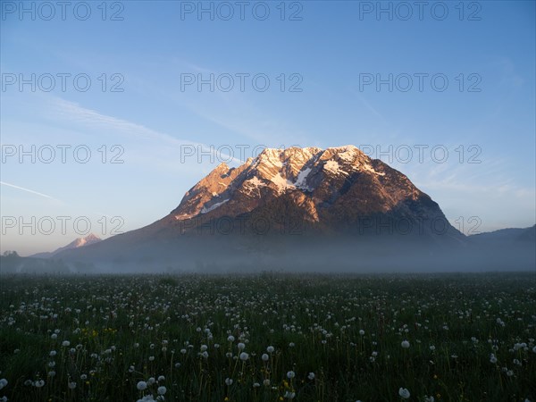 Morning light falls on a mountain peak, Grimming, early morning fog on the meadow, near Irdning,