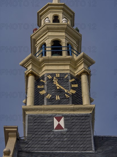 Close-up of a clock on a historic clock tower with blue and yellow decoration, tower with a golden