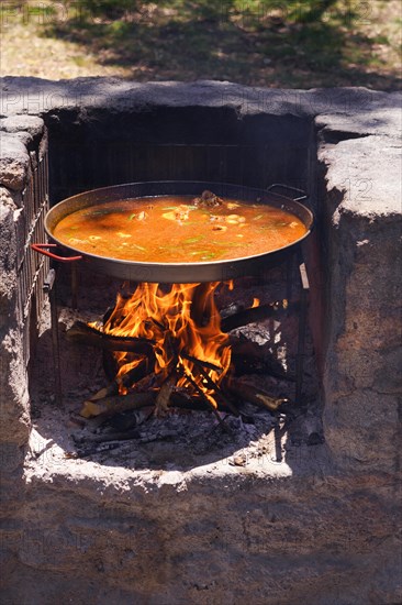 Close-up of a paella pan with a typical Spanish paella cooking on the fire in the countryside