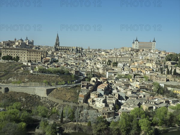 Historic old town with a river landscape and striking church towers, framed by hills, under a clear