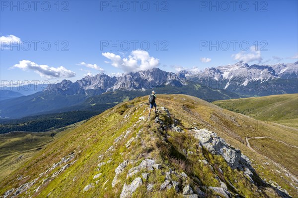 Mountaineers on a hiking trail between green mountain meadows on a mountain ridge, mountain