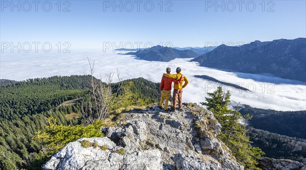 Two friends put their arms around each other's shoulders, mountaineers on the rocky summit of the