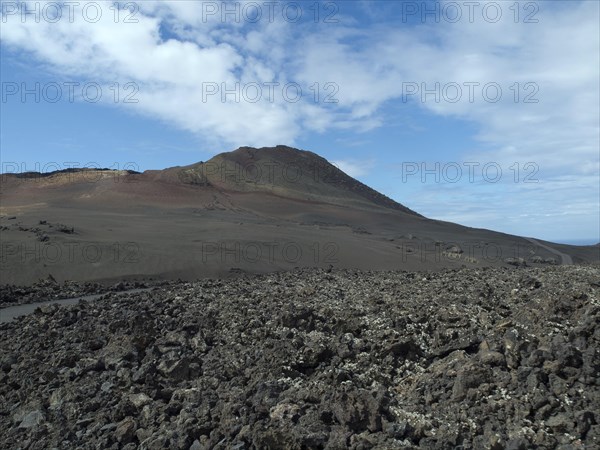 Vast desert landscape with volcano in the background and blue sky, barren landscape of lava