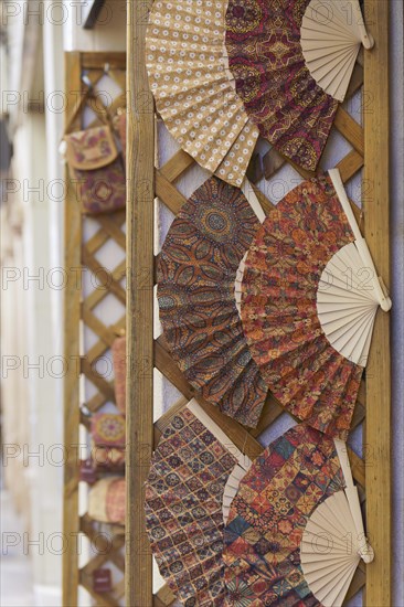 Colorful handmade fans typical of spain displayed in a store in the street