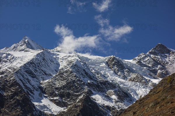 Snowy mountains and glaciers under a blue sky with some clouds, snow on high mountains in the alps,