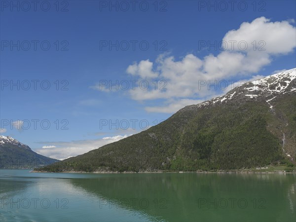 Clear water, snow-capped mountains and blue sky in a peaceful landscape, greenish shimmering water