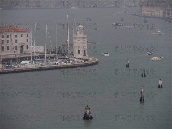 Venetian harbour with boats and yachts and a harbour wall surrounded by a foggy atmosphere, church
