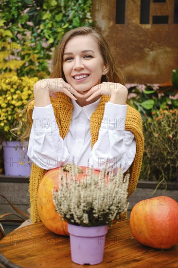 Satisfied smiling woman sitting at a table on the terrace with her chin on her hands