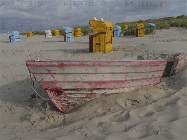 Red boat in the sand with scattered beach chairs and dunes, peaceful atmosphere, colourful beach