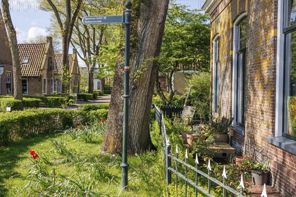An idyllic village with manicured gardens, blooming flowers and a street sign, historic houses and