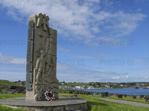 Stone memorial with flowers in a cemetery with a view of the surrounding landscape and sky, old