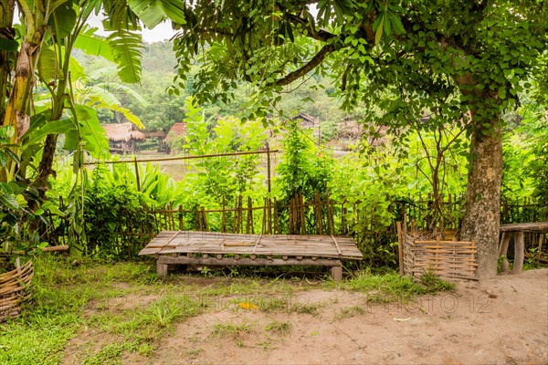 Wooden table in front of bamboo fence in small southeast Asian farming community in Chiang Khan,