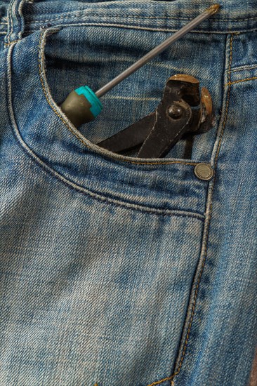 Jeans with a screwdriver and pliers sticking out of the pocket