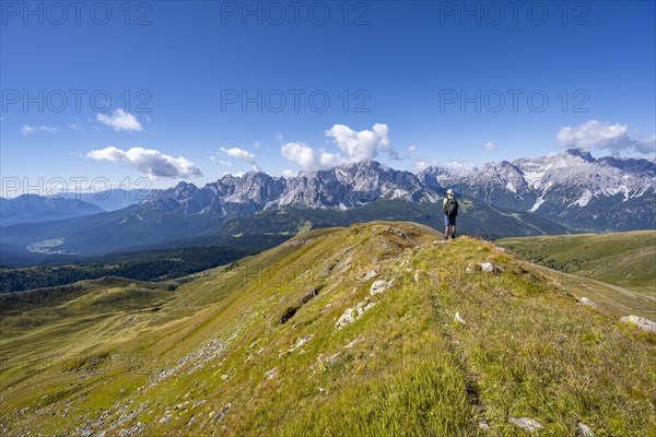 Mountaineers on a hiking trail between green mountain meadows on a mountain ridge, mountain