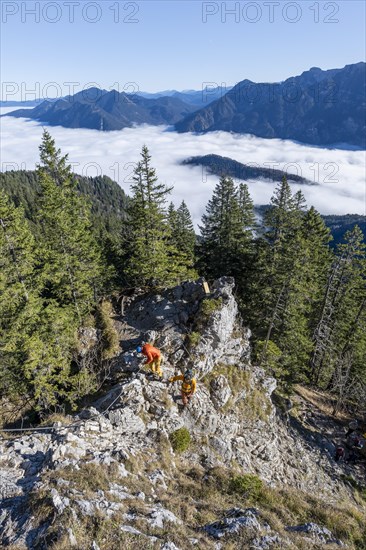 Two friends, mountaineers climbing the via ferrata to the rocky summit of the Ettaler Manndl, view
