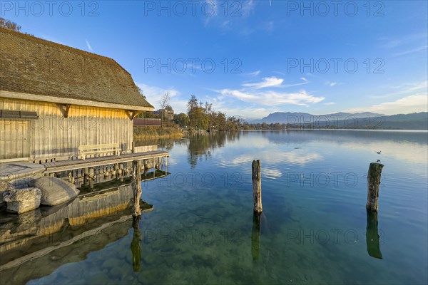 Boathouse on Lake Sempach with reflection in the water and clear sky, Sempach, Lucerne,