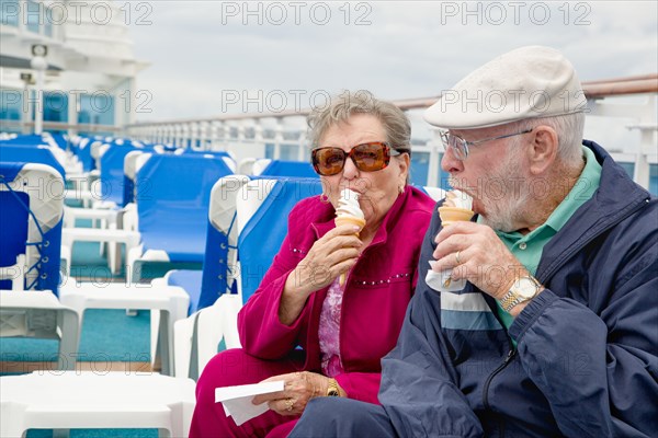 Happy senior adult couple enjoying ice cream on the deck of a luxury passenger cruise ship